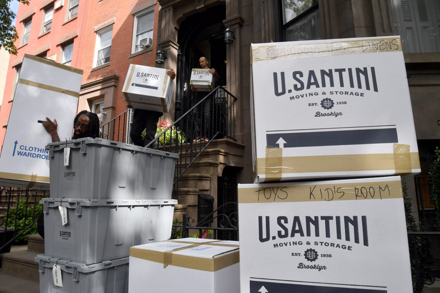 U.Santini movers carrying boxes down some stairs