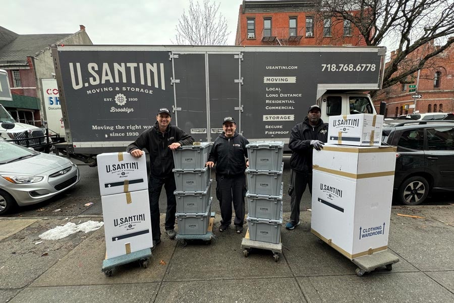 U.Santini movers with packed boxes standing in front of moving truck